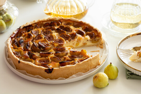 Delicious freshly baked fig tart with creamy filling and golden crust presented with fresh figs and tea