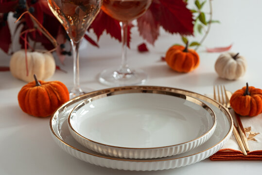 Festive Thanksgiving table setting with mini pumpkins, elegant plates, and wine glasses for holiday celebration
