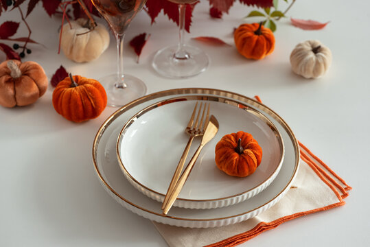 Elegant Thanksgiving Table Setting with Decorative Pumpkins and Golden Cutlery