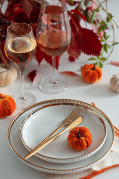 Elegant Thanksgiving Table Setting with Pumpkins Wine Glasses and Golden Cutlery