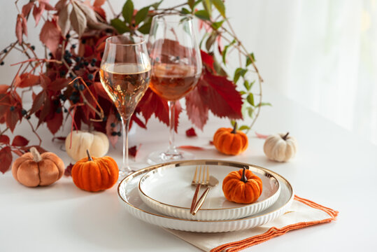 Festive Thanksgiving Table Setting with Pumpkins Wine Glasses and Autumn Foliage Decoration