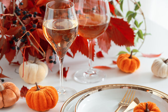 Elegant Thanksgiving table setting with wine glasses and decorative pumpkins festive autumn celebration