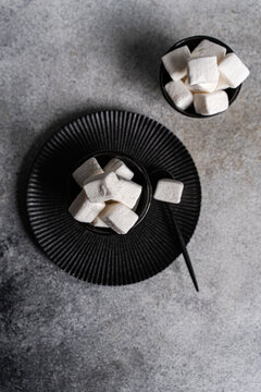 Marshmallow sweet on black plate with spoon and bowl