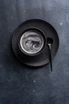 Black coffee cup with cream swirl on textured table