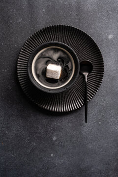 Black coffee with marshmallow on dark textured table