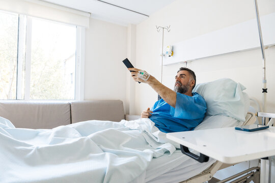 Patient recovering in hospital bed watching television
