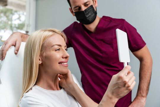 Medical professional discussing aesthetic treatment results with a satisfied client in a modern cosmetic surgery consultation room.