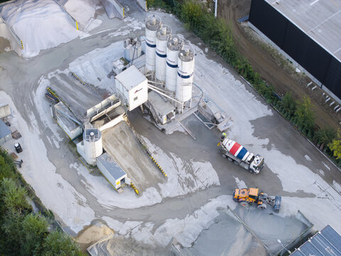 Krakow, Malopolska, Poland - 16 September 2026: Aerial view of CEMEX concrete plant with storage silos, a concrete mixer truck, and heavy machinery in an industrial facility.