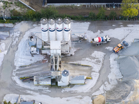 Krakow, Poland - 16 September 2026: Aerial view of CEMEX concrete batching plant with industrial silos, a cement mixer truck, and construction machinery on site.