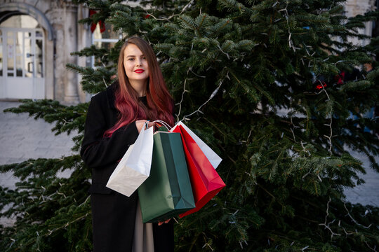 Woman with shopping bag beside Christmas tree in town