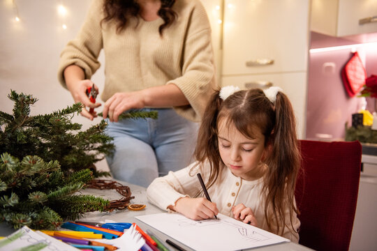 Mother and daughter make Christmas wreath and draw at home