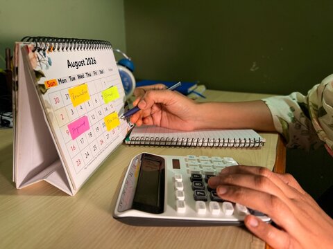 Business women using calculator and desk calendar to plan Tax payments, deadlines, budgets and financial schedules concept