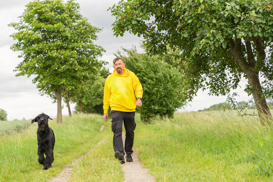 Man walk with black dog along country path