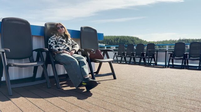 A woman relaxes on deck chairs on a cruise ship at Valaam, Lake Ladoga. This cozy moment evokes a happy, peaceful, and joyful feeling.