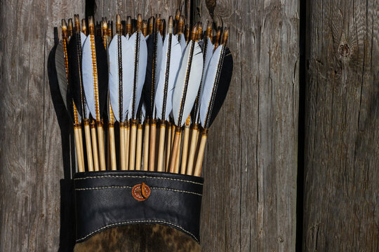 Traditional archery equipment: Wooden arrows with natural goose feathers and wooden cams in a leather bow quiver. 