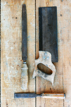 Worn hand saw file and chisel on wooden workbench