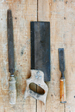 Worn hand saw, file and chisel on wooden workbench