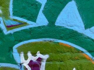 Geometric street art detail in green cyan and white on wall © LilliM