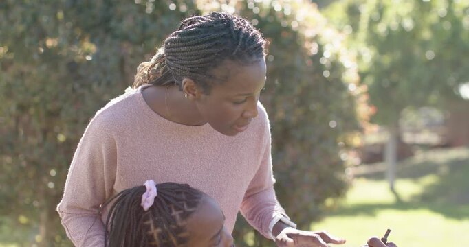 Family checking PV panel in yard, woman leaning over child urging man fixing with screwdriver
