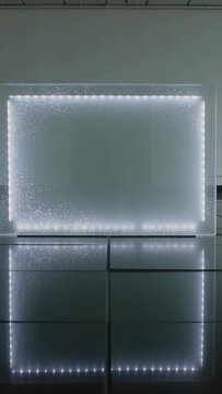 Vertical video: Powering LED panel showing rising dots in demo room, tiled floor reflection