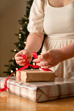 Woman tie red ribbon bow on Christmas gift