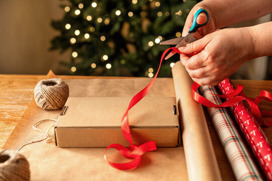 Hands cut ribbon for Christmas gift packaging
