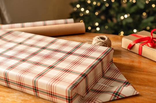 Christmas gift wrapping with plaid paper near decorated tree