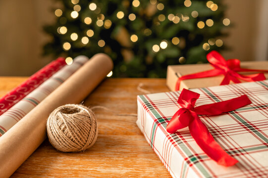 Christmas gift wrapping with ribbon beside decorated tree