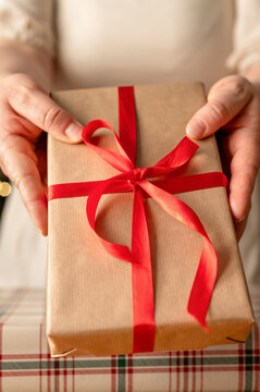Hands holding wrapped Christmas gift with red ribbon