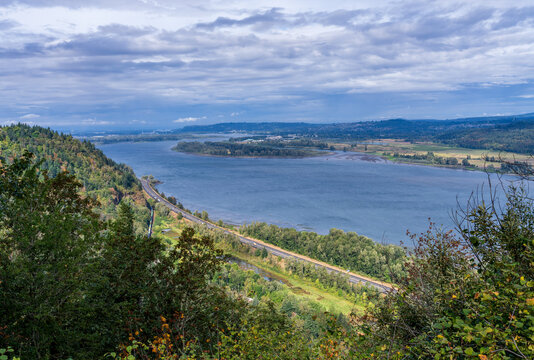Elevated view of the Columbia River and Interstate 84 with train winding through forested bluffs seen from Crown Point in Multnomah County, Oregon.