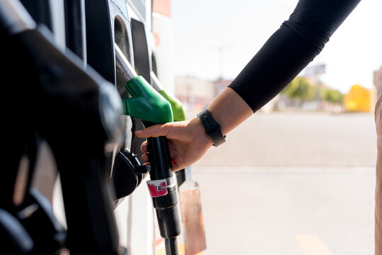 Woman hold fuel nozzle at gas station during refueling