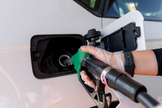 Hand refueling white car with gasoline at gas station