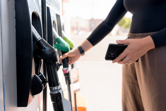 Woman select gasoline nozzle at self-service fuel station