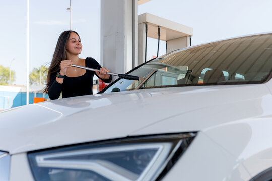 Woman clean car windshield at self-service wash station