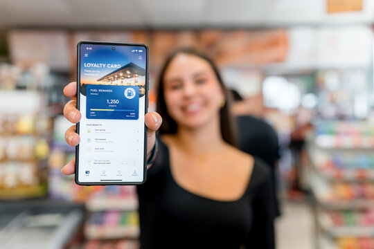 Woman show fuel rewards loyalty card app on smartphone