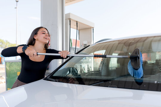 Woman clean car windshield at self-service wash station
