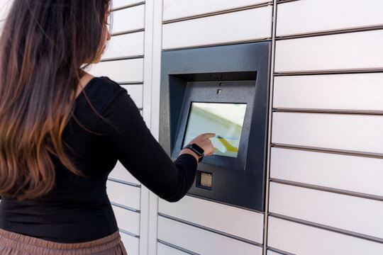 Woman use parcel locker touchscreen for package shipment