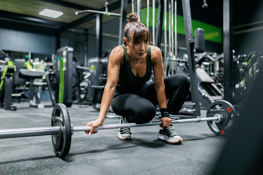 Woman prepare for barbell deadlift in modern gym