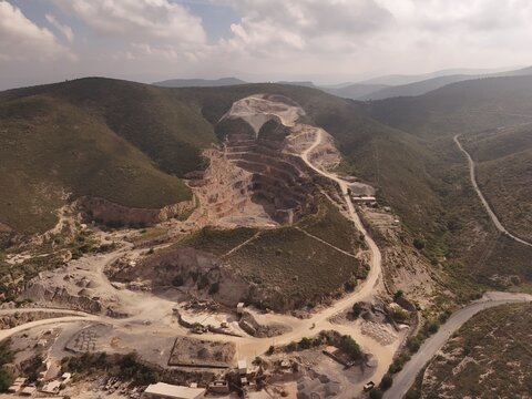 Toliman Municipality, Mexico - 19 September 2026: Aerial view of Caleras de Bernal quarry showing terraced excavation levels, dusty access roads, and surrounding arid hills.