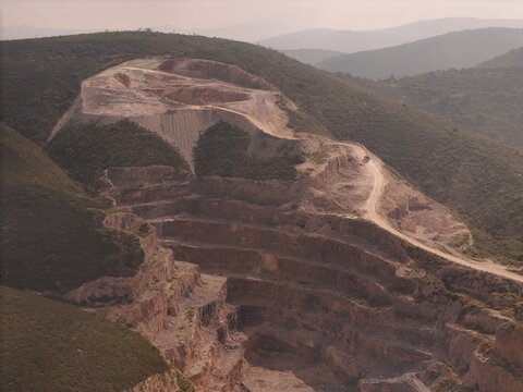 Toliman Municipality, Queretaro, Mexico - 18 September 2026: Aerial view of Caleras de Bernal, an open-pit limestone quarry with terraced levels, dirt access roads, and arid mountain landscape.