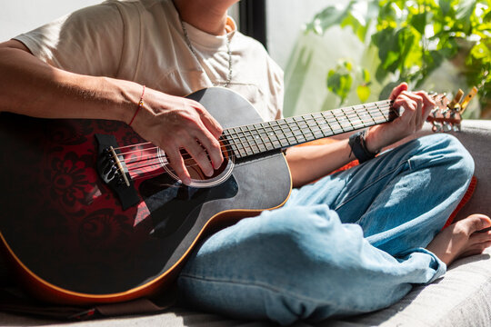 Musician play acoustic guitar at home in sunlight