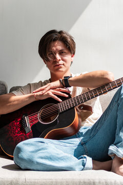 Young musician relaxing with acoustic guitar at home