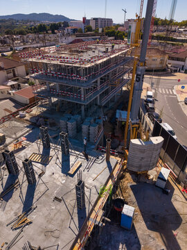 Barcelos, Braga, Portugal - 18 September 2026: Aerial view of a construction site with a multi-story building, scaffolding, a tall yellow crane, and workers in an urban area.