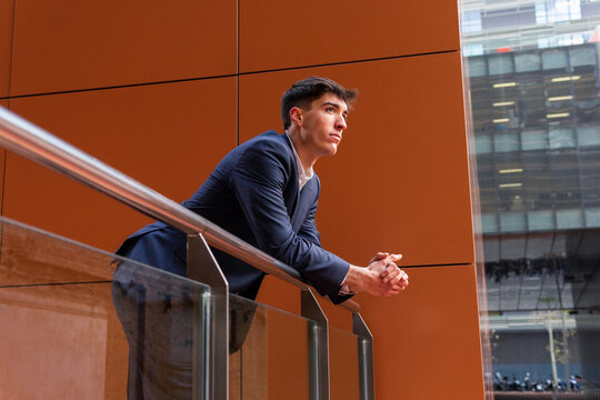 Young entrepreneur overlooking city from modern office balcony