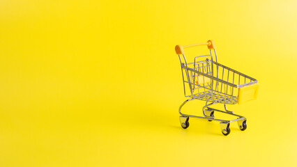 Yellow miniature shopping cart on yellow background with copy space on the left. Concept for retail ecommerce online shopping and consumerism.  © wibiwisnu