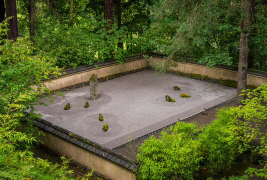 Zen rock garden featuring moss covered stones and raked gravel enclosed by traditional walls at the Portland Japanese Garden in Oregon.
