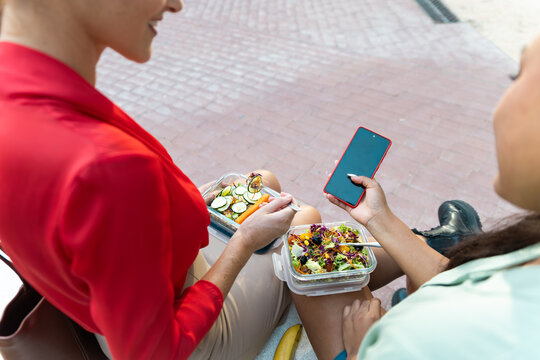 Business women enjoy healthy lunch and smartphone break