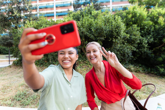 Business women take smartphone selfie afterwork in city park