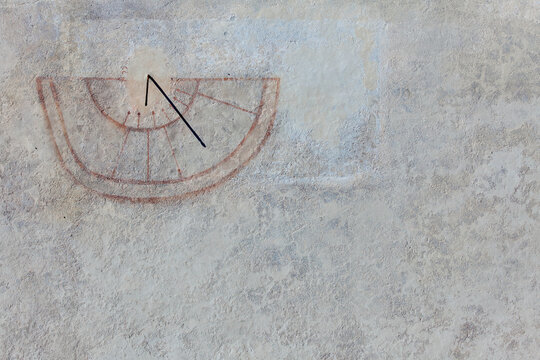 Sundial on a weathered stone wall ancient timekeeping and history concept rustic mountain architecture detail with faded plaster and traditional craftsmanship