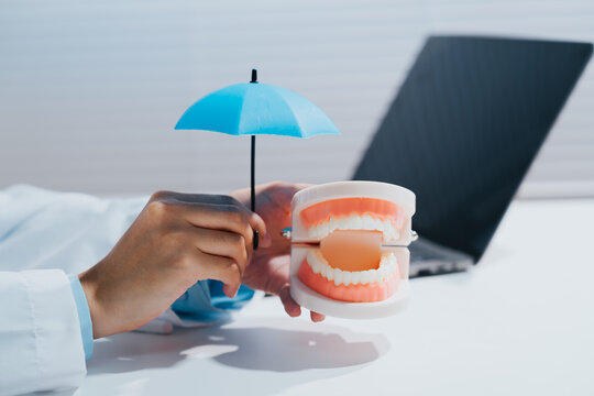 Dental insurance protection coverage umbrella model teeth patient safety, professional dentist feeling secure with healthy oral care plan
